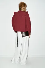 Blusa de manga larga con cuello redondo, volantes en los hombros y detalle de jaretas frontales. Presenta bordados perforados en toda la prenda y cierre posterior con botones ocultos.