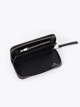 Maxi billetera de cuero vacuno con diseño matelassé en forma de V. Presenta un aplique metálico dorado en forma de labios en el frente y cierre perimetral con tirador de cuero.