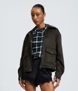 Campera bomber de gamuza sintética color verde oliva, con cuello estructurado, cierre frontal con botones metálicos y bolsillos delanteros con solapa.