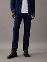 Jeans de denim azul índigo oscuro, corte slim fit, talle medio y pierna estrecha.
