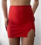 Minifalda negra de crepe, tiro alto, corte ajustado y tajo lateral.