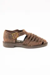 Sandalias cangrejeras de cuero color marrón, con diseño de tiras cruzadas y cierre de hebilla metálica en el lateral. Poseen suela plana y gruesa.