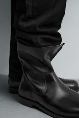 Bota de caña media fabricada en piel color marrón oscuro, con cierre de cremallera lateral, horma cuadrada y suela con ligero tacón.