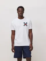 Remera de algodón orgánico color blanco, con corte regular fit y detalle de bordado en forma de X con diseño geométrico multicolor en el pecho.