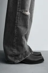 Bota estilo cowboy de caña media, color negro, con punta cuadrada, tacón bajo y cierre lateral.