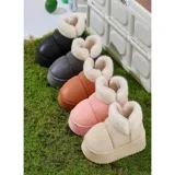 Pantuflas botitas color tostado con diseño acolchado y plataforma, forradas con corderito sintético blanco en el interior y el cuello. Cuentan con una pequeña etiqueta decorativa en el lateral.