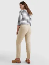 Pantalón chino color beige de sarga elástica, corte slim, con cierre de cremallera y botón, bolsillos traseros de ojal y logo de Tommy Hilfiger bordado en la parte trasera.