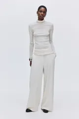 Pantalón de tiro alto con piernas amplias y corte recto. Presenta cierre frontal con botón oculto, bolsillos laterales al bies y bolsillos traseros insertados, con pliegues marcados en la parte delantera y trasera.