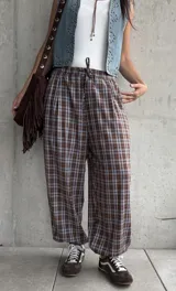 Pantalón babucha de corte holgado, con estampa de cuadros en tonos marrón y celeste, cintura elástica con cordón ajustable y puños fruncidos en los tobillos.