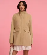 Campera alargada de Blue Steel confeccionada en polivelour, con cuello alto, capucha desmontable, cierre frontal oculto y bolsillos con solapa. Presenta un diseño minimalista y elegante con recortes delanteros.