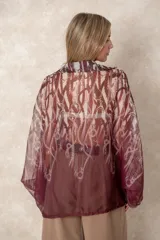 Camisa oversize de gasa con estampado de cadenas en tonos bordó y rosado. Presenta cuello clásico, cierre frontal con botones y mangas largas con puños abotonados.