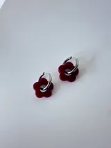 Aros de acero quirúrgico plateado tipo argolla con dije colgante en forma de flor color bordó.