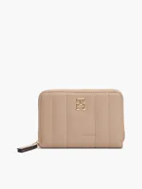 Billetera Tommy Hilfiger color beige con diseño acolchado, cierre de cremallera, múltiples ranuras interiores para tarjetas, compartimento interior para billetes, bolsillo interior con cierre de solapa e insignia del monograma TH dorada en la parte delantera.
