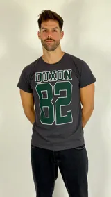Remera de algodón color gris con estampa frontal estilo deportivo que incluye el texto DUXON y el número 82 en color verde con borde blanco.