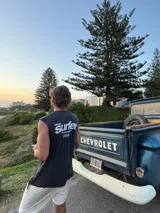 Musculosa sin mangas color negro lavado (negro wash) con estampado frontal que dice "Glassy Surfer" y un pequeño gráfico debajo.