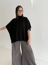 Poncho de tejido de punto color marrón chocolate, con cuello alto tipo polera y mangas cortas amplias. Presenta un diseño holgado con terminaciones acanaladas en el ruedo.