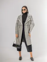 Sacón tipo tapado de corte recto y largo midi, con diseño de estampa pied de poule y solapas clásicas. Confeccionado en tejido abrigado y liviano, ideal para media estación.