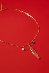 Collar de cadena fina en tono dorado con dijes colgantes: un pez con acabado martillado, una perla pequeña y un cristal verde engarzado.
