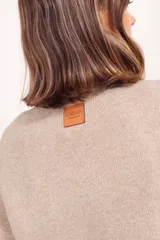 Buzo de punto en color gris oscuro, con cuello redondo acanalado, mangas largas con puños ajustados y diseño de corte holgado.