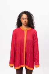 Saco de punto con diseño de bloques de color en tonos rojos y fucsias, con terminaciones en color naranja. Presenta cuello redondo, cierre frontal con botones y mangas largas.