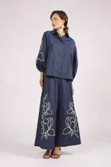 Pantalon de corte ancho y tiro alto, color azul marino, con bordados florales en color crema en la parte inferior de las piernas.