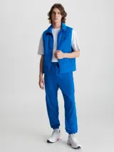 Chaleco acolchado azul eléctrico con cierre frontal, cuello alto y logo de Calvin Klein en el pecho.