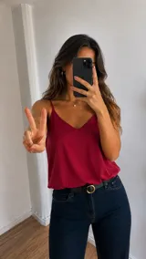 Blusa bordó de tirantes finos con escote en V, confeccionada en tela satinada.