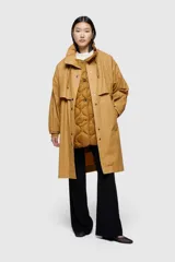 Chaqueta larga color marrón de corte holgado, confeccionada en tejido encerado lavado. Incluye chaleco interior extraíble en nailon ligero acolchado.