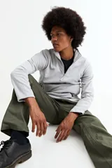 Buzo de polar gris con cuello alto y cierre frontal parcial, de manga larga y ajuste cómodo.