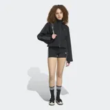 Campera corta Adidas SST 2.0 de color negro, con capucha, cierre frontal de cremallera bidireccional y las clásicas tres tiras en las mangas.