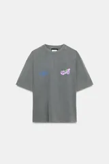 Camiseta de algodón con efecto lavado, corte oversize, cuello redondo y manga corta. Presenta estampados gráficos en el frente.
