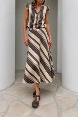 Falda midi confeccionada en mezcla de lino con diseño de rayas diagonales en tonos marrón y beige. Presenta un corte evasé con vuelo y caída fluida.
