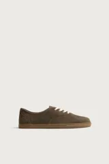 Zapatilla deportiva barefoot fabricada en piel con acabado serraje de color marrón, con cordones en contraste y suela fina de goma.