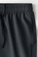 Pantalón deportivo de corte estándar y piernas rectas, confeccionado en tejido funcional ripstop con tecnología DryMove para absorción de sudor. Presenta cintura elástica con cordón oculto, bolsillos laterales con cierre y detalles perforados en los laterales de las piernas.