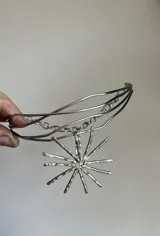 Gargantilla plateada con dije de sol colgante.