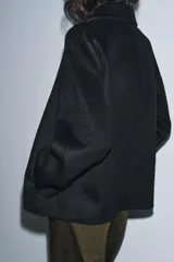 Chaqueta de corte recto confeccionada en mezcla de lana, color negro. Presenta cuello solapa, manga larga y cierre frontal con botones a tono.
