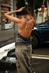 Top tipo chaleco de denim ahumado color azul, con escote halter, cierre frontal con lazo y dos bolsillos tipo cargo con estribos de bronce.