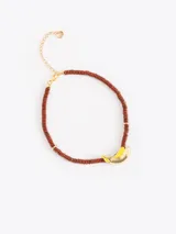Collar de cuentas de piedra marrón con dije en forma de banano dorado y amarillo. Cuenta con cadena de extensión dorada.
