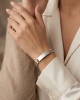 Pulsera de eslabones tipo reloj con placa central lisa para grabar, combinando tonos plateado y dorado.