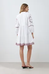 Vestido midi blanco con bordados de flores en el escote, mangas y ruedo.