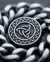 Pulsera de eslabones gruesos de acero con dije central circular que presenta un diseño de nudo celta en relieve.