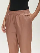 Pantalón negro de cuero sintético con cintura elástica y corte recto.