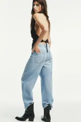 Pantalón de jean celeste claro, corte cropped, tiro medio, con trabillas y cinco bolsillos. Cierre frontal con cremallera y botón metálico.