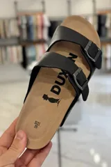 Sandalias Duxan de color negro, con dos tiras ajustables con hebillas metálicas y plantilla anatómica tipo corcho.