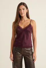 Blusa de satén color bordó con escote en V decorado con encaje y tirantes finos ajustables. Presenta un detalle de encaje en el ruedo.