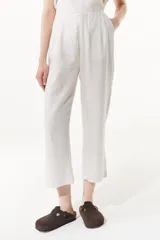 Pantalón culotte color crudo, confeccionado en lino metalizado, con cintura alta y bolsillos laterales. Presenta pespuntes a contratono en cintura, bolsillos laterales y traseros.