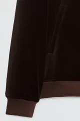 Cazadora de terciopelo de algodón color marrón oscuro, con cuello solapa, cierre frontal de cremallera y bolsillos frontales de vivo. Presenta rib elástico a tono en puños y bajo.