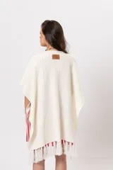 Ruana de tejido en color crudo, de diseño abierto con flecos en el ruedo inferior y detalles bordados.