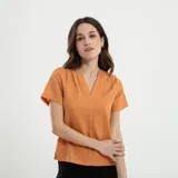 Blusa verde de manga corta con escote en V profundo y textura acanalada o plisada verticalmente. Corte holgado.