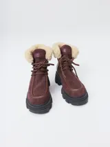 Botas estilo borcego Mutma modelo Anga de cuero color bordo, con plataforma y suela track negra. Cuenta con detalles de corderito sintético en la caña y cordones marrones.